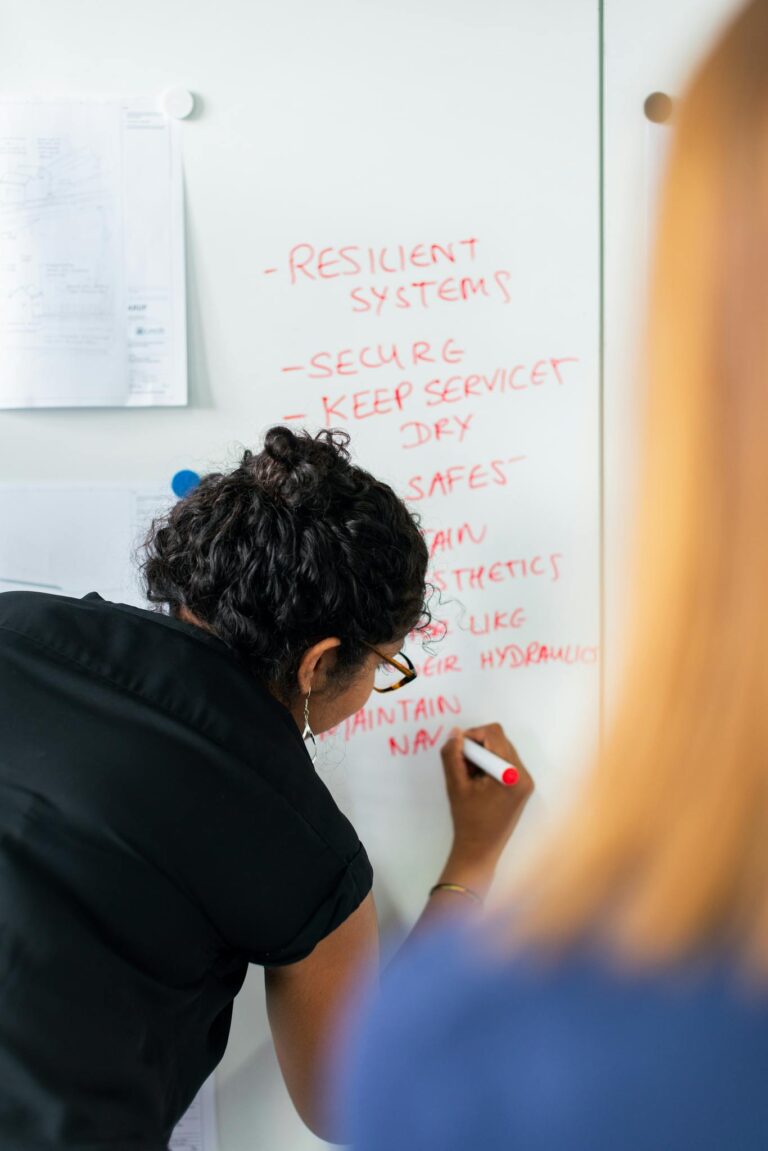 Female engineer writing strategy on a whiteboard during a business meeting.